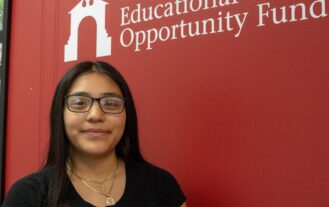 Ossiris Garcia stands in front of a Ramapo College EOF logo.