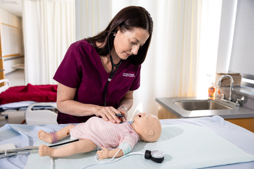 Spizzo stands over a simulated newborn in the lab listening to its heartbeat
