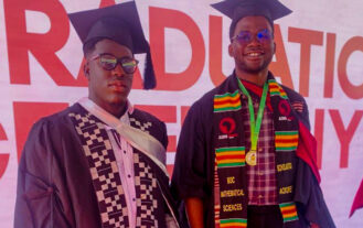 Two graduates stand side by side in black caps and gowns.