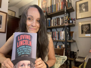 Woman poses with a book in front of her.