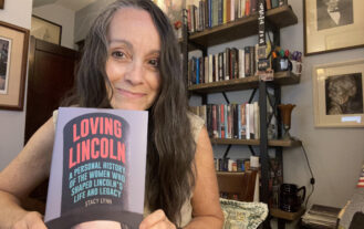 Woman poses with a book in front of her.