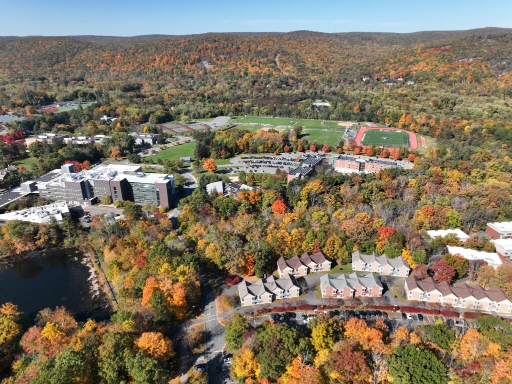 Aerial view of campus during the fall showing the athletics fields, residence halls, academic buildings, and Ramapo Mountains with green, orange, red, and yellow foliage.