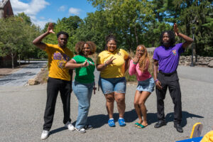 A group of five college students stand and smile.