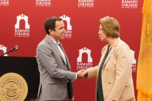 A man and a woman shake hands in front of a podium.