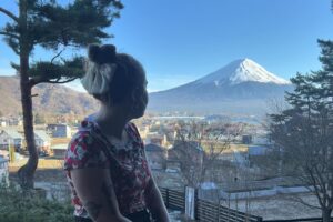 A young woman sits, looking toward a snow-capped mountain.