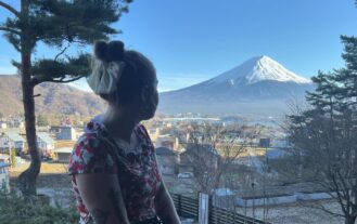 A young woman sits, looking toward a snow-capped mountain.