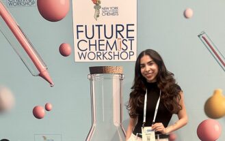 A woman stands behind a sign that reads, Future Chemist Workshop
