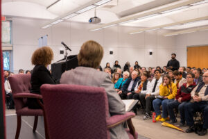 A man stands up in a crowd of college students to ask a question.