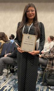 A woman stands holding a certificate.