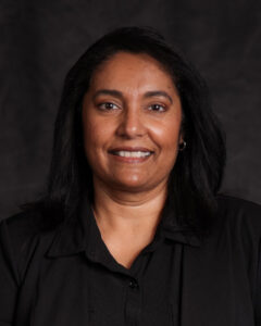 A headshot of a woman with dark hair and a black shirt.