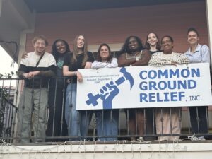 A group of college students stand together behind a banner stating, Common Ground Relief.