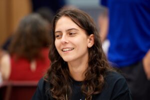 A young woman sits and smiles.