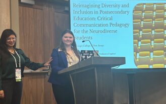 A woman stands at a podium with a screen behind her, as another woman stands next to her.