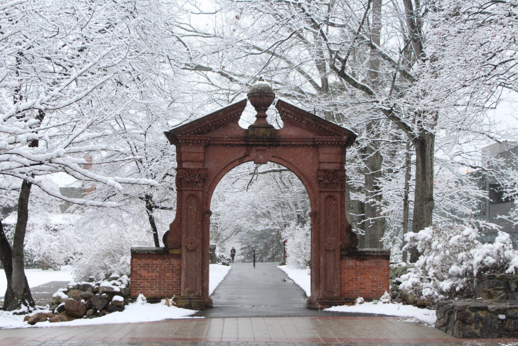 The Havemeyer Arch on the campus of Ramapo College is surrounded by trees with branches covered in snow.