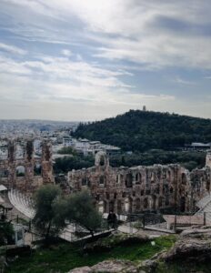 A large historic structure stands in front of the mountains.
