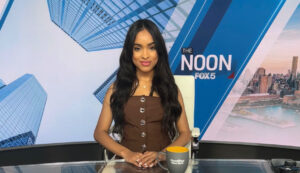 A woman sits at a news desk.