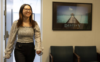 A woman walks into a room, On the wall hangs a picture with the word Destiny on it.