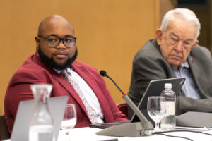 Trustee Lally is seated at the BOT table alongside Trustee Dator.