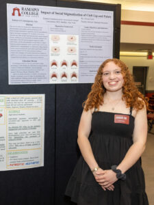 A woman stands next to a poster and smiles.