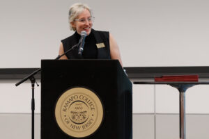 A woman stands at a podium and smiles as she speaks.