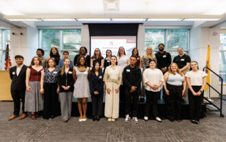 The graduating College Honors program students stand in two rows in front of a screen with the program logo at the 2026 College Honors Senior Symposium held on April 15, 2026