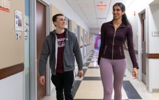 A man and a woman walk down a hallway together and smile at eachother.