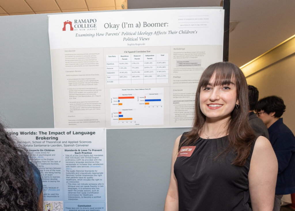 Sophia stands to the right of her research poster at the 2025 Scholars Day.