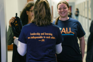 Sarah and classmates are talking, all wearing navy blue and gold Sophomores Advancing In Leadership (S.A.I.L.) t-shirts.