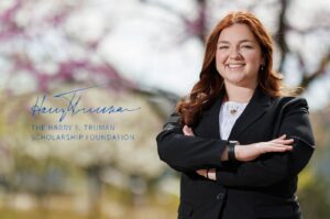 Sarah Glisson '26 is wearing a black suit and light colored top. Her arms are crossed across her chest and she is smiling.