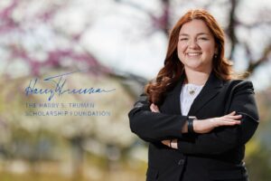 Sarah Glisson '26 is wearing a black suit and light colored top. Her arms are crossed across her chest and she is smiling.