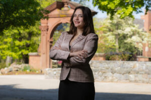A woman poses outside with her arms crossed.