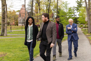 Four men walk on a path outside.