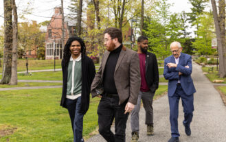 Four men walk on a path outside.