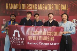 A group of five young men stand side by side and hold a large maroon banner with the words American Association of Men in Nursing, Ramapo College of New Jersey.