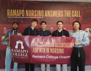 A group of five young men stand side by side and hold a large maroon banner with the words American Association of Men in Nursing, Ramapo College of New Jersey.