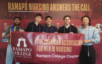A group of five young men stand side by side and hold a large maroon banner with the words American Association of Men in Nursing, Ramapo College of New Jersey.