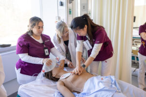 Nursing students in the on-campus clinical simulation lab provide CPR to a sim patient, supervised by faculty.