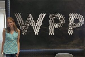 A woman stands next to a sighn with the letters WPP.