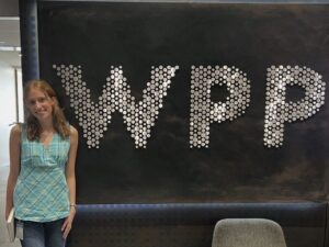 A woman stands next to a sighn with the letters WPP.