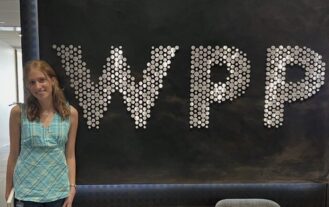 A woman stands next to a sighn with the letters WPP.