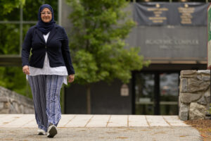 A woman walks outside in front of a building.