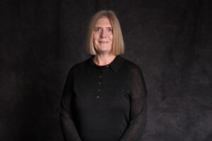 A woman stands against a black backdrop.