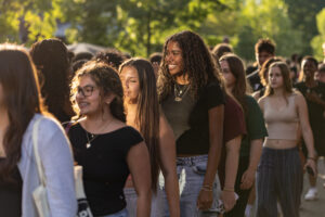 A line of college students walk and smile.