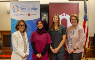 Standing in front of two banners displaying the Bergen New Bridge Medical Center and Ramapo College logos, from left to right: Bergen New Bridge President and CEO Deborah Visconi, Aamena Ismail BSN '29, Ava Picinic BSN '29, and Ramapo College President Cindy Jebb