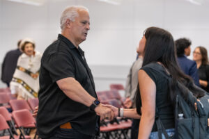 A young woman shakes hands with an older man and looks up at him.