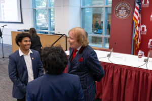 Three men stand together and talk.
