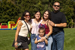 A family of 5 stands together outside. They are smiling.
