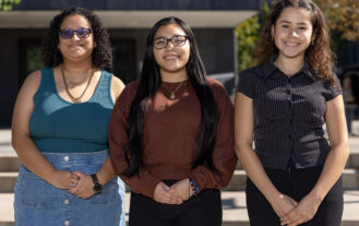 A group of three college students stand side by side.