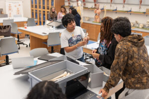 College students work with models of bones inside of a lab.