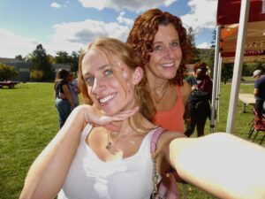 A young woman poses with her mom outside. They are both smiling.